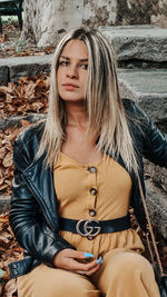 Portrait of young woman sitting against wall