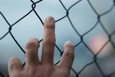 Cropped image of person hanging on chainlink fence