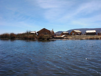 Houses by sea against blue sky