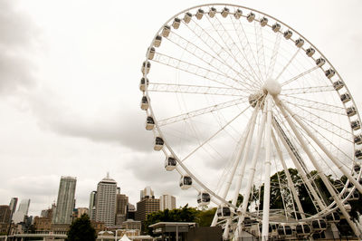 Low angle view of ferris wheel against buildings