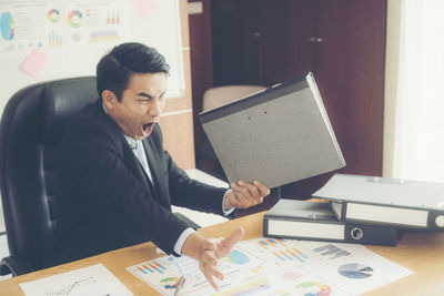 Young man using mobile phone while sitting on table