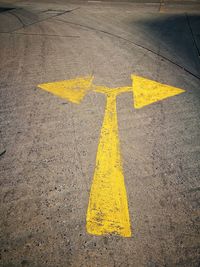 High angle view of yellow arrow sign on road