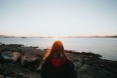 Rear view of woman looking at sea against clear sky