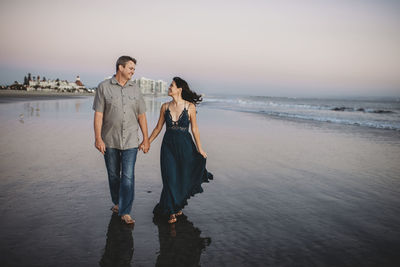 Young couple standing on beach against sky