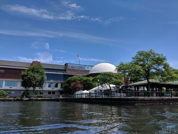 Buildings at waterfront against cloudy sky