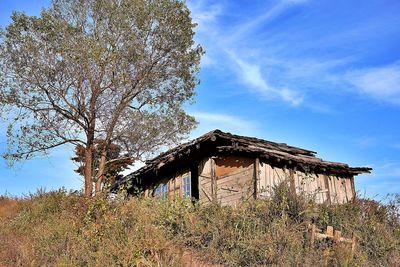 Exterior of abandoned house on field against sky