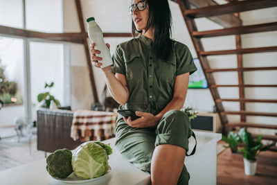 Midsection of woman holding smart phone at home