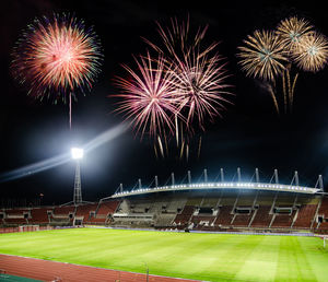 Low angle view of firework display over stadium at night