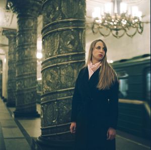 Thoughtful woman looking away while standing against colonnade