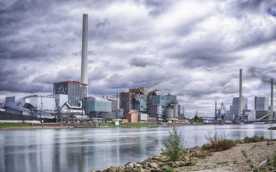 View of factory by city against sky