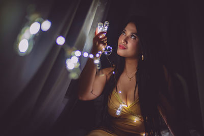 Close-up of woman holding illuminated lights at night