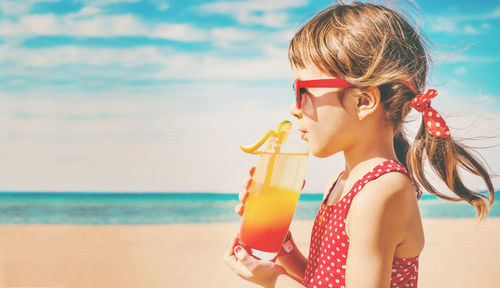 Portrait of young woman wearing sunglasses while standing against sea