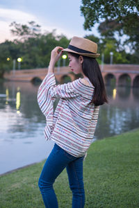 Young woman wearing hat while standing by lake