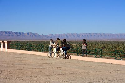 People riding bicycle against clear sky