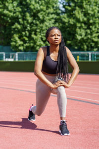 Persistent black woman with long braids tries hard to pump gluteal muscles taking care of fit body