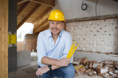 Portrait of smiling man holding camera at construction site