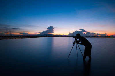 Silhouette male photographer at calm sea