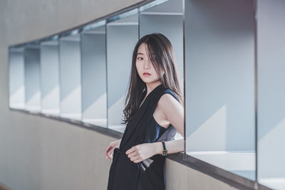 Portrait of woman standing against wall