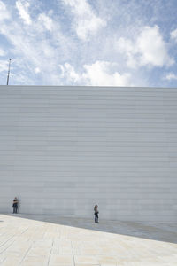 Rear view of people walking on building in city against sky