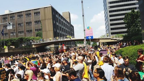 Crowd on street in city against sky