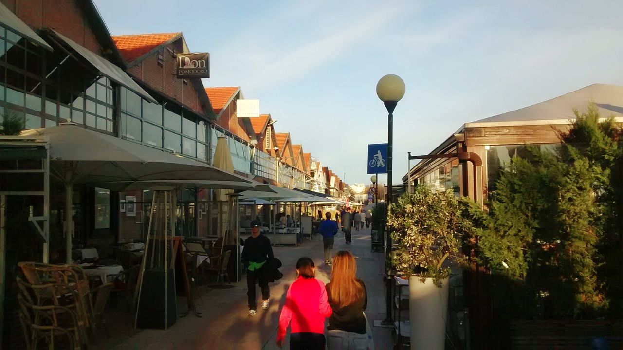 architecture, built structure, building exterior, men, person, lifestyles, sky, walking, leisure activity, large group of people, street light, railing, city, street, tree, outdoors, city life, incidental people, day