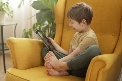 Boy using mobile phone while sitting on sofa at home