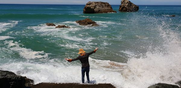 Man with arms outstretched standing in sea