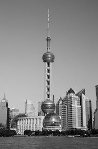 Communications tower in city against clear sky