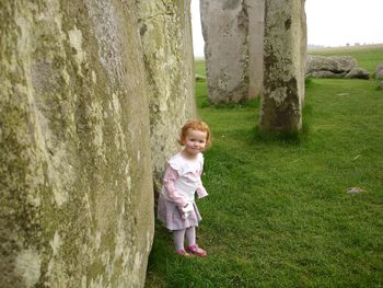 Portrait of smiling girl standing on tree trunk