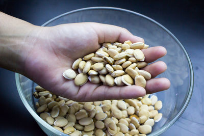 Close-up of hand holding beans over bowl