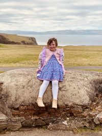 Full length of girl standing on field against sky