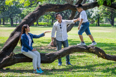 Full length of a boy with arms raised on tree