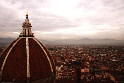 View of cityscape against cloudy sky
