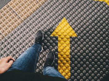 Low section of man walking by arrow sign on footpath