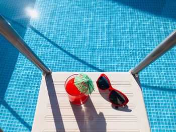 High angle view of drink and sunglasses by swimming pool