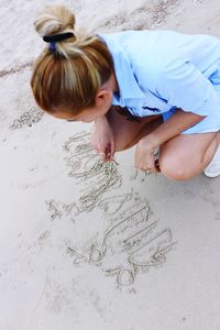 High angle view of woman writing in sand at beach