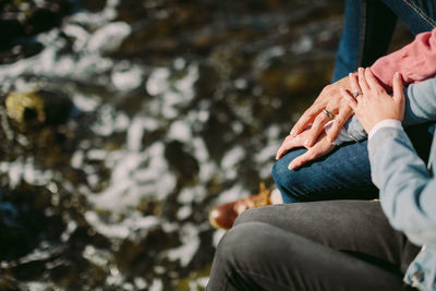 Midsection of couple sitting over river