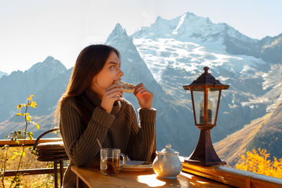 Girl drinks tea and eats in the mountains