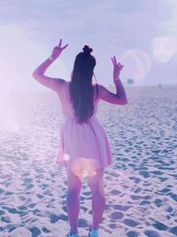 Rear view of woman standing on beach against sky