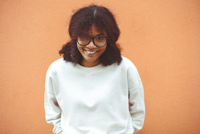 Portrait of young woman standing against yellow wall