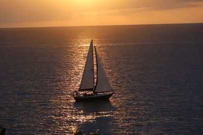 Sailboat moving in sea against sky during sunset