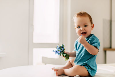 Spring portrait of a boy with a bouquet of flowers. the baby holds snowdrops in his hand and smiles