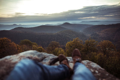 Low section of man on mountain against sky