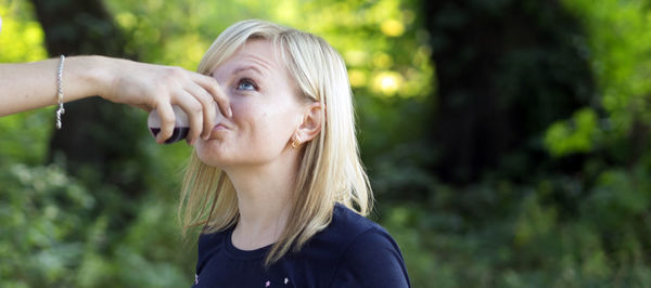 Woman drinking juice from cropped hand