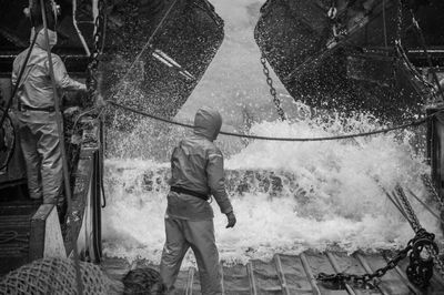 Rear view of men working in water