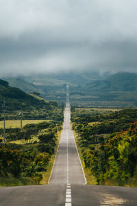 High angle view of empty road leading towards mountains against sky