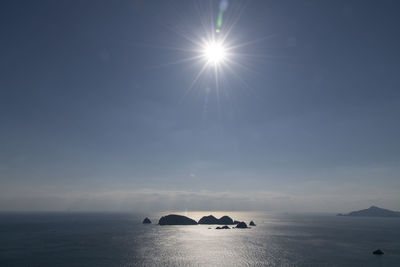 Sunlight streaming through rocks in sea against sky