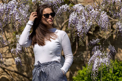 Low angle view of woman standing by flowering tree