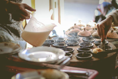 Midsection of person pouring batter in containers