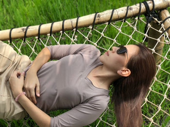 Young woman lying down on fence against plants